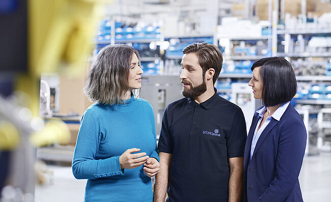 Two women and a man talking in a factory