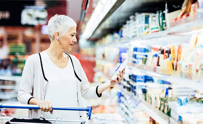 Eine Frau steht vor dem Kühlregal im Supermarkt